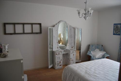 a bedroom with a mirror and a bed and a chair at casa Rosalba in Strigno