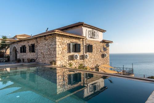 a house with a swimming pool next to the ocean at Xigia Beach Residence villas in Orthoniaí