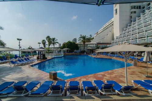 uma piscina com espreguiçadeiras azuis e um hotel em Club Hotel Tiberias - Suites Hotel em Tiberias