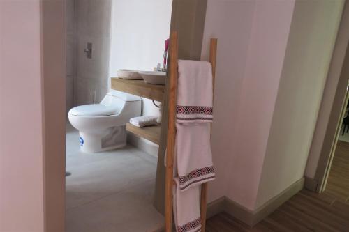 y baño con aseo, lavabo y toallas. en TEYFA Hospedaje - Departamento, en Atuntaqui