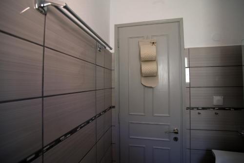 a bathroom with a white door and a towel rack at Nicola's Apartments in Kassiopi