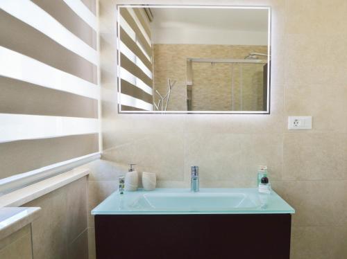 a bathroom with a sink and a mirror at Rova Apartment in Malinska