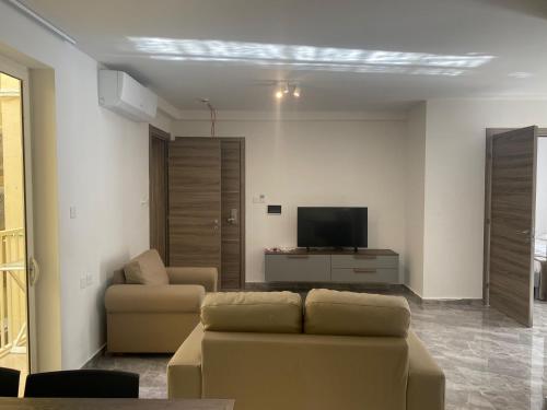 a living room with a couch and a tv at Sir William Strand in Il-Gżira