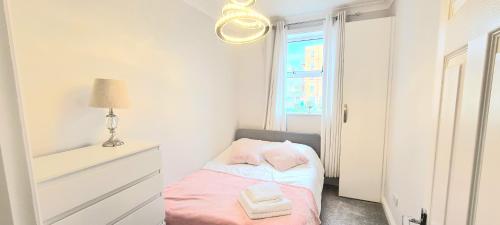 niewielka sypialnia z łóżkiem i oknem w obiekcie Spacious 3 bed flat near the sea with parking w Bournemouth