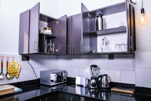 a kitchen with purple cabinets and a black counter top at Sereneville 4 Deluxe Bukoto-Kisaasi Apartment in Kampala