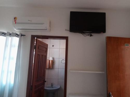 a bathroom with a television on the wall and a toilet at Pousada Algaroba in Bom Jesus da Lapa