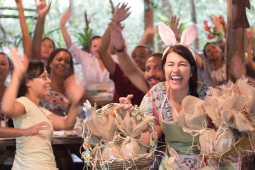 a group of people sitting at a table with their hands in the air at Hotel Pousada Praia do Farol in Ilha do Mel