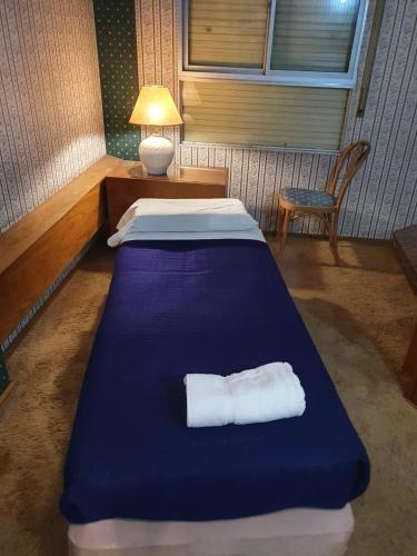 niebieskie łóżko w pokoju z lampką i krzesłem w obiekcie Apartamentos Plaza w mieście Rosario