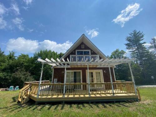 a small house with a large deck in a field at Mountain Adventure Ski Chalet near Gore in Johnsburg