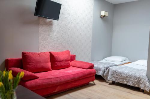 a living room with a red couch and a bed at Pod Beczką in Augustów