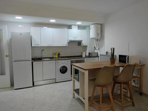 eine Küche mit weißen Geräten sowie einem Tisch und Stühlen in der Unterkunft Mar y Montaña - l'Hospitalet de l'Infant in Vandellòs i l’Hospitalet de l’Infant