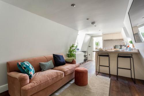 a living room with a brown couch and a kitchen at East Street Apartments, The Lanes Brighton in Brighton & Hove