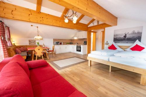 a living room with two beds and a red couch at Alphirt Ferienwohnungen in Fischen
