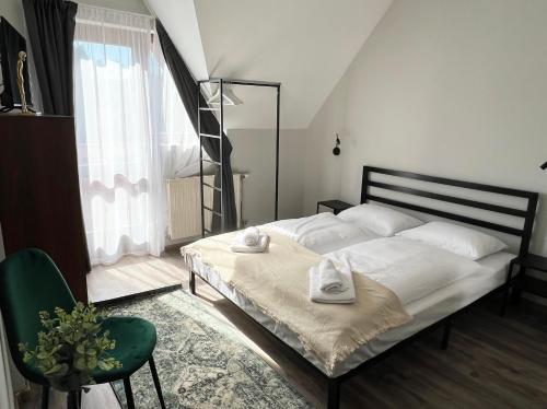 um quarto com uma cama branca e uma cadeira verde em Nussbaum Panzió em Keszthely