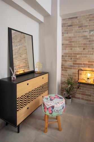 a bedroom with a dresser with a mirror and a stool at Silvia's Apartments in Corfu Town