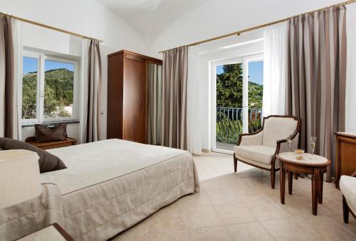a bedroom with a bed and a chair and windows at Hotel Villa Ceselle in Anacapri