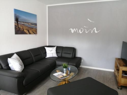 a living room with a black couch and a table at Bude im Windrosenweg in Cuxhaven