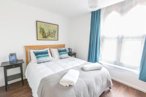 a bedroom with a large white bed with blue curtains at Chester Stays - Lovely apartment in the heart of Chester with free parking in Chester