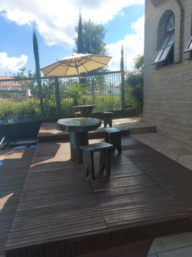 a patio with a table and benches and an umbrella at Casa de Pedra-Vale dos Vinhedos -RS in Monte Belo