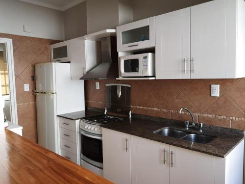 a kitchen with white cabinets and a sink and a refrigerator at Precioso Departamento - Excelente ubicación in Mendoza