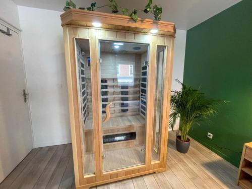 a wooden cabinet in a room with a plant at Superbe appartement-Sauna-Cinéma-Parking-Gare in Amiens