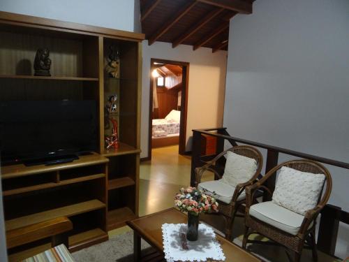 Una sala de estar con dos sillas y un televisor. en San Pietro, en Gramado