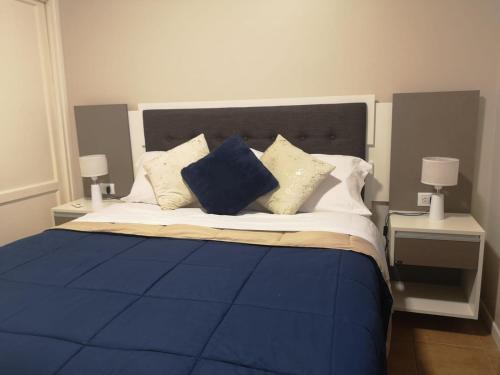 a bed with blue and white pillows on it at Precioso Departamento - Excelente ubicación in Mendoza