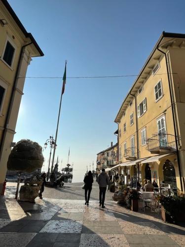 two people walking down a street next to buildings at Affittacamere Bardolino in Calmasino