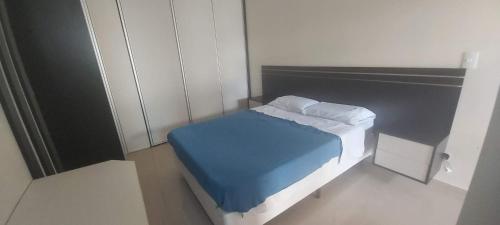a small bedroom with a bed with a blue blanket at APTO NOVO PÉ NA AREIA - Praia do Sonho, Itanhaém in Itanhaém