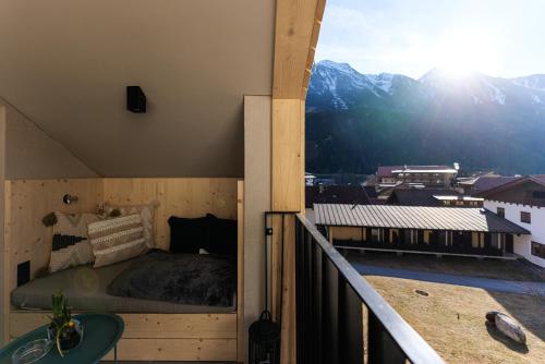 a bedroom with a bed on a balcony with mountains at Lebe`oetz - Das Ferienapartmenthaus im Zentrum von Oetz in Oetz