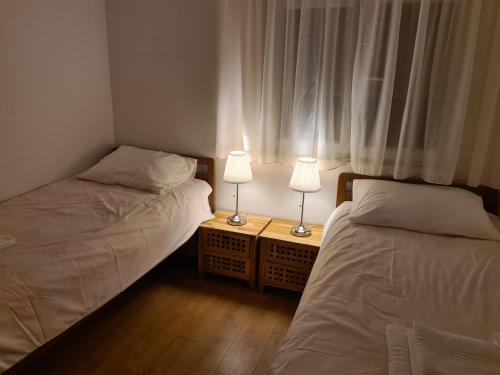 two beds in a room with two lamps on tables at Apartman Lucija Međugorje in Međugorje
