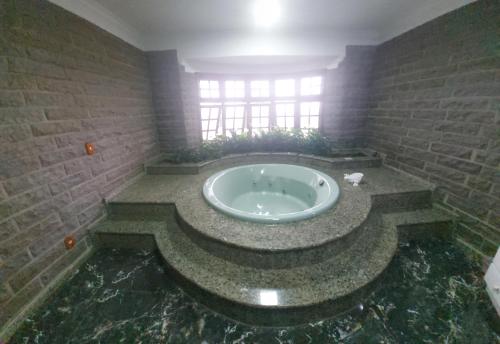 a bathroom with a large tub in a brick wall at Casa de Pedra-Vale dos Vinhedos -RS in Monte Belo