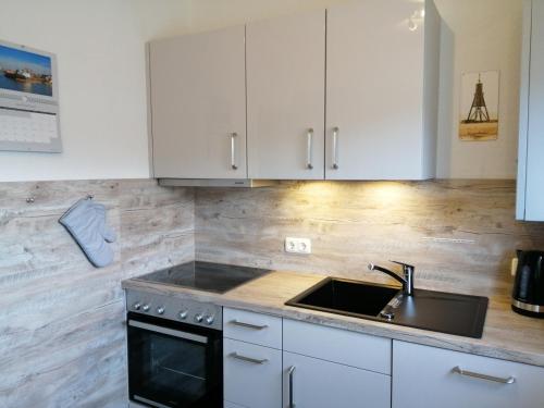 a kitchen with white cabinets and a sink at Bude im Windrosenweg in Cuxhaven