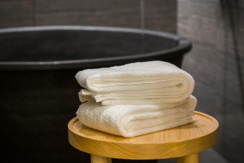 a pile of towels sitting on a table in front of a tub at Hotel Ryumeikan Ochanomizu Honten in Tokyo