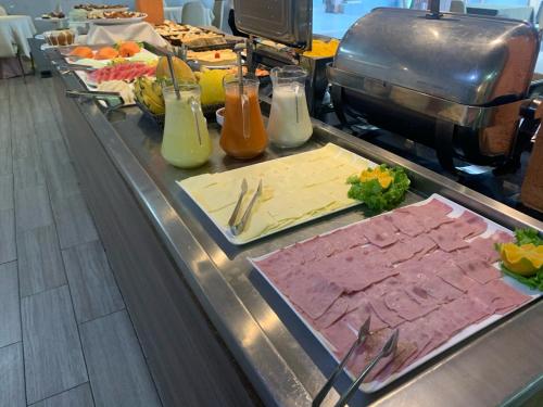 a buffet line with meat and vegetables and drinks at HANNA Arcos d'Atalaia Hotel - Aracaju in Aracaju