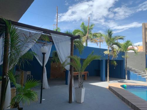 a patio with palm trees and a blue building at HANNA Arcos d'Atalaia Hotel - Aracaju in Aracaju