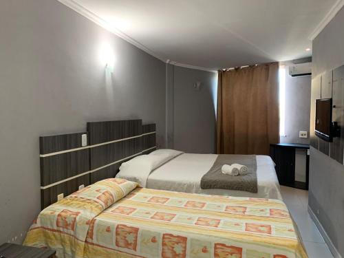 a small bedroom with a bed and a television at HANNA Arcos d'Atalaia Hotel - Aracaju in Aracaju
