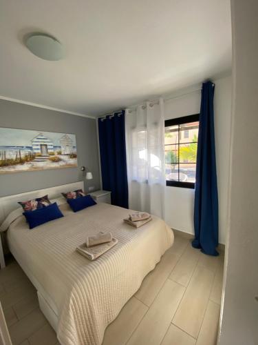 - une chambre avec un lit doté de rideaux bleus et d'une fenêtre dans l'établissement Fuerte Holiday M&M Apartaments 2, à Costa Calma