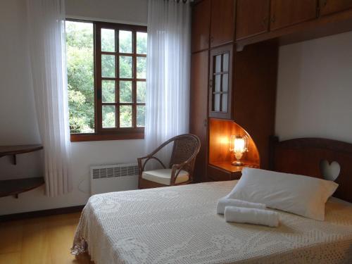 - une chambre avec un lit, une fenêtre et une chaise dans l'établissement San Pietro, à Gramado