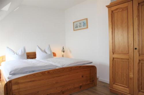 Schlafzimmer mit einem Holzbett mit weißer Bettwäsche und Kissen in der Unterkunft Apartment Lüdicke in Kirchdorf