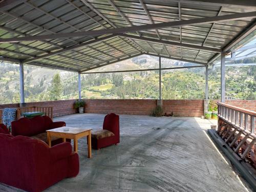 een grote afgeschermde veranda met rode stoelen en een tafel bij Eco Hotel Banderas in Huaraz