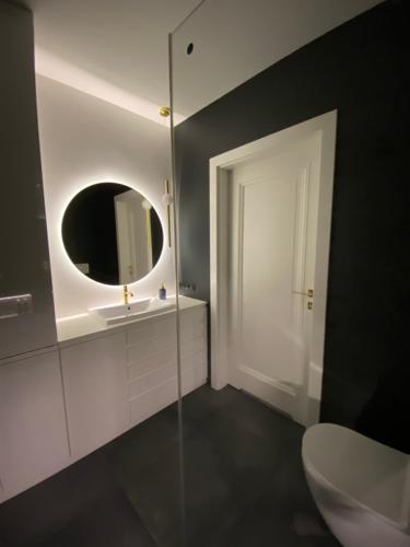 a bathroom with a white toilet and a mirror at Apartament Złote Noce in Augustów