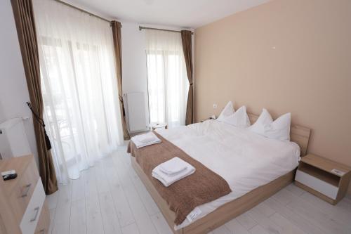 a bedroom with a large white bed with two towels on it at CENTRAL VIEW Craiova in Craiova
