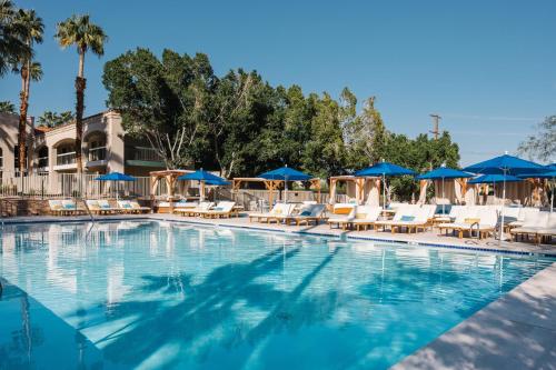 a swimming pool with chairs and blue umbrellas at L3 Oasis Hotel in Palm Springs