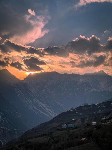 a sunset over a mountain range with mountains in the background at La Hault in Sissu
