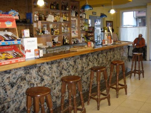 un bar con taburetes de madera en una tienda en Hostal la Cuesta, en Vega de Espinareda