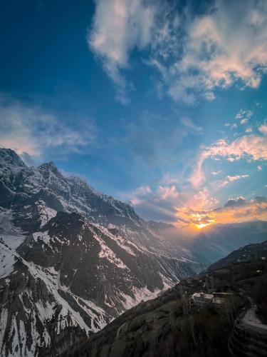 a view of a snowy mountain range with the sun setting at La Hault in Sissu