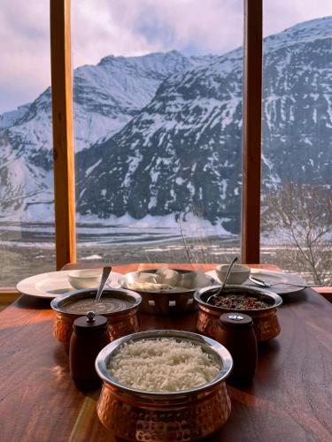 a table with bowls of food on a table with a mountain at La Hault in Sissu