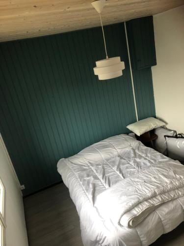 Cama blanca en habitación con pared verde en Maison port de la guittière, en Talmont
