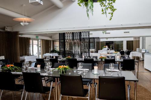 a dining room with tables and chairs with flowers on them at Hotel Svanen Billund in Billund